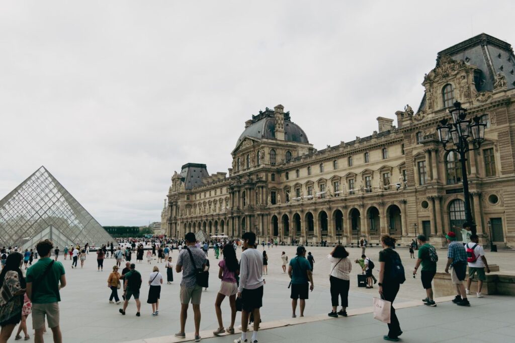Crafting Captivating Headlines: Your awesome post title goes here Visitors gather at the Louvre Museum in Paris with the iconic glass pyramid in view.