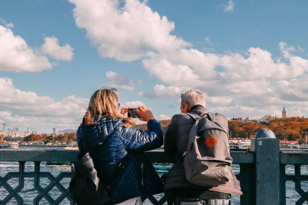 The Art of Drawing Readers In: Your attractive post title goes here Two adults enjoying the view from a bridge, capturing scenic river sights under a vibrant sky.